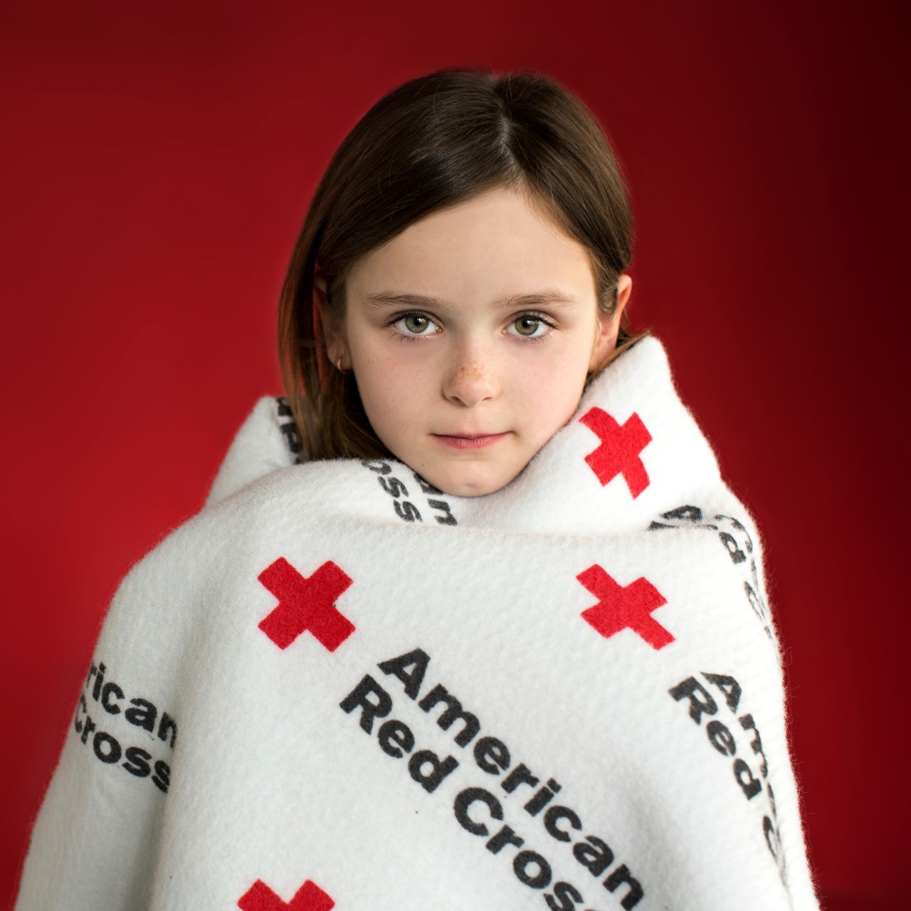 Young girl wrapped in a The Renewed Hope Foundation blanket.