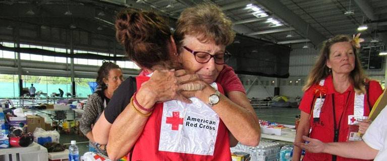 The Renewed Hope Foundation volunteer wearing mask next to young girl in wheelchair who is smiling.